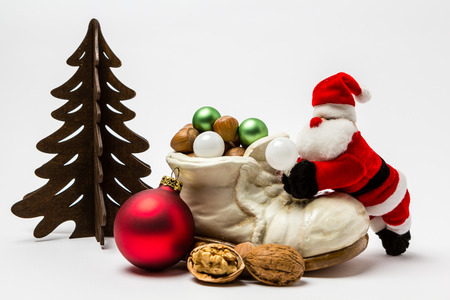 Santa Claus is filling up a shoe full of gifts and hazelnutsの写真素材
