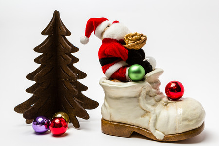 Santa Claus is sitting on a shoe full of gifts holding a walnutの写真素材