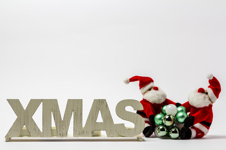 XMAS white lettering on a white background with Christmas balls and a Santa Claus.の写真素材