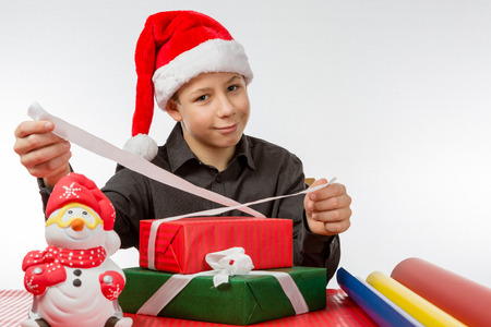 Boy laughing binds a loop around colored Christmas presentsの写真素材