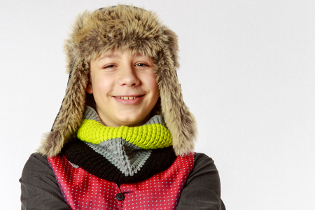 Boy with winter cap and scarf smiles happily, portraitの写真素材
