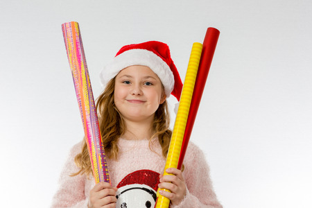 Girl with Christmas cap holds up wrapping paperの写真素材