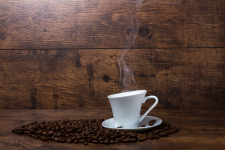 Hot aromatic coffee with black beans on wooden tableの写真素材