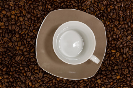 Empty cup on brown coffee beansの写真素材