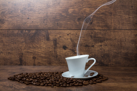 Hot aromatic coffee with black beans on wooden tableの写真素材