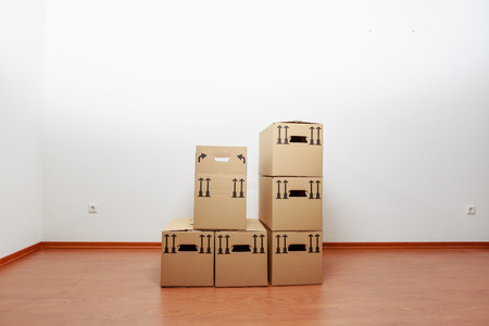 Boxes in empty white room on wooden parquet