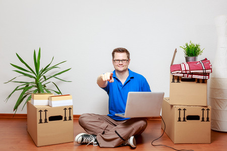 Young man uses laptop in his new homeの写真素材