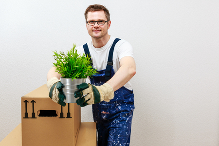 man in blue overall presenting a green plantの写真素材