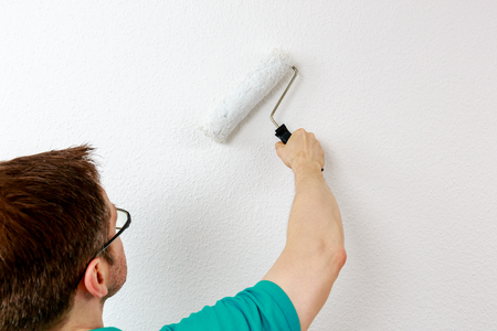 Man paints wall in white, close upの写真素材