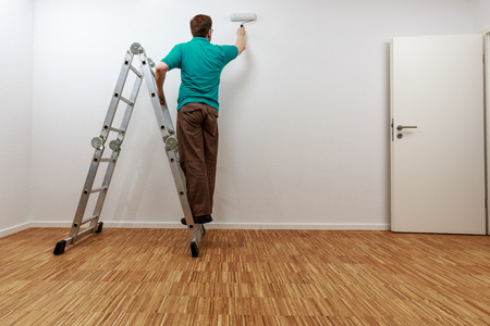 Man on ladder while painting the wallの写真素材