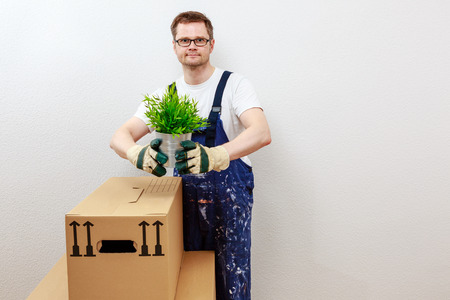 man in blue overall presenting a green plantの写真素材