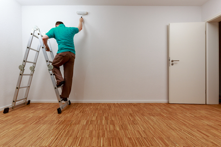 Man on ladder while painting the wallの写真素材