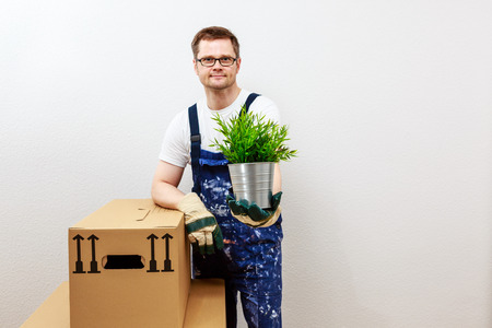 man in blue overall presenting a green plantの写真素材