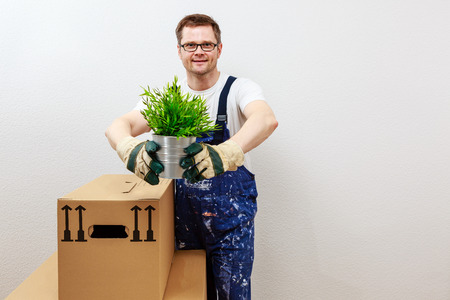 man in blue overall presenting a green plantの写真素材