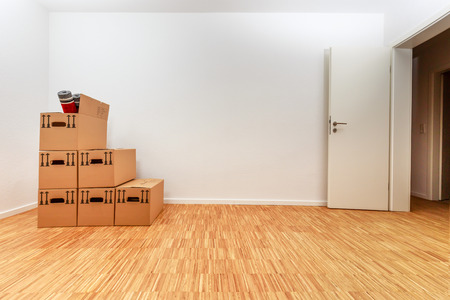 Moving cartons in empty white room with wooden parquetの写真素材