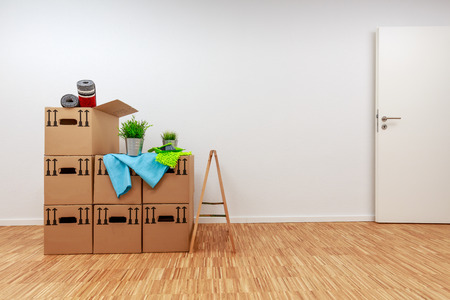 Moving cartons in empty white room with wooden parquetの写真素材