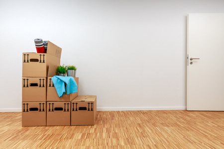 Moving cartons in empty white room with wooden parquetの写真素材