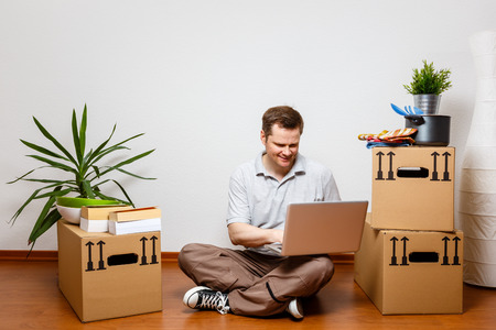 Young man using laptop in his new homeの写真素材