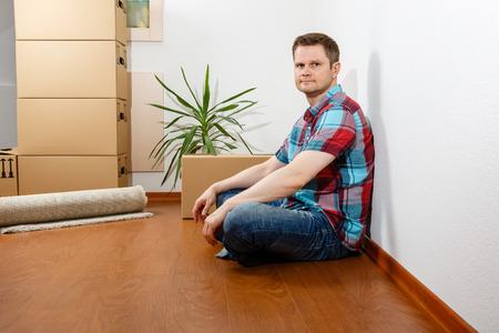 Man sitting leaning against a white wall and relaxingの写真素材