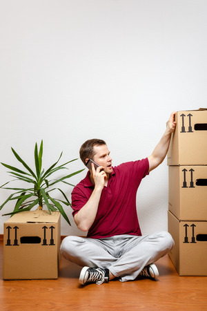 Man sits on the floor and talks on mobile phoneの写真素材