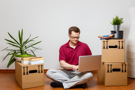 Young man using laptop in his new homeの写真素材