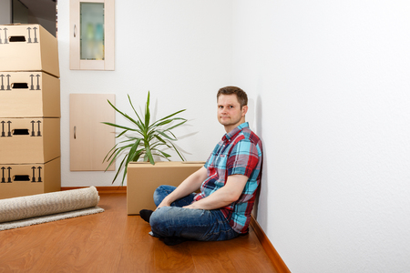 Man sitting leaning against a white wall and relaxingの写真素材
