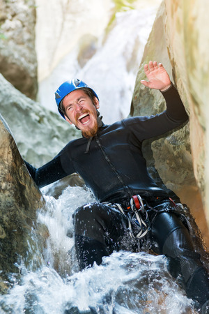 Excited man climbing cliff in canyon with rope.の写真素材