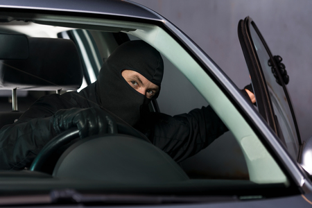 Car thief entering a parking car and going away with it.の写真素材