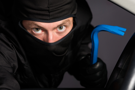 Burglar with unrecognizable face breaking in a car at night.の写真素材
