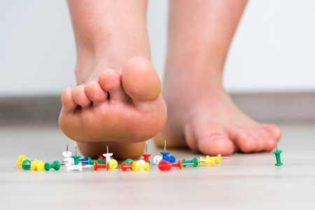 Female foot above colored pushpinの写真素材