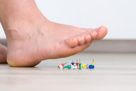 Female foot above colored pushpin