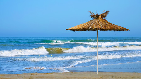 Deserted seashore with a lonely beach sunshade during an evening surf on a clear day.の写真素材