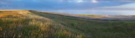 Panoramic landscape of grassy plains, the sky and the lake in the morning.の写真素材