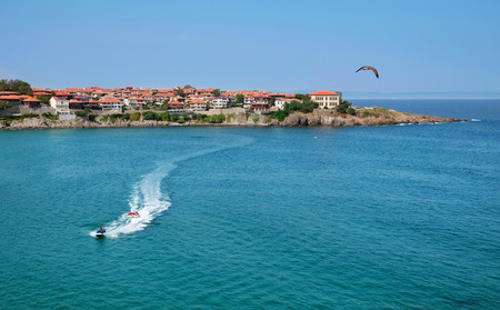 Landscape with the view of the part of old Sozopol town surrounded by the sea. There is an jet ski and vacationers in the sea. Bulgaria, the Black Sea coast.の写真素材