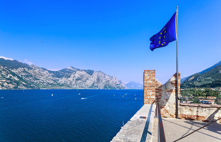 European Union flag on the background of lake Garda and Malcesine town.の写真素材