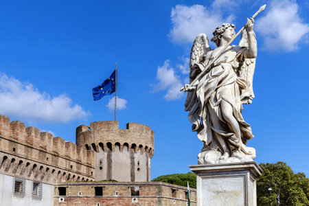 ROME, ITALY - OCTOBER 8, 2018: Marble statue of an angel with a spear against the background of part of the Castle of the Holy Angel and the flag of the European Union.のeditorial素材