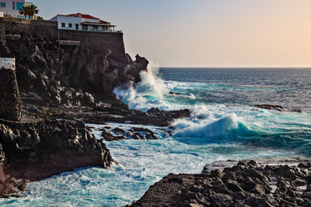 Playa San Juan, Tenerife, Spain - February 17, 2019: Evening view of the shore with volcanic rocks...