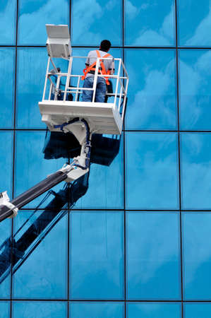 Window washing on high-rise office building in crane beam
