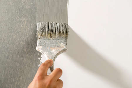 Paintbrush painting wall in gray close-up