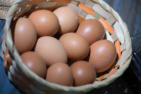 closeup of basket with chicken eggs. rustic table in the background.