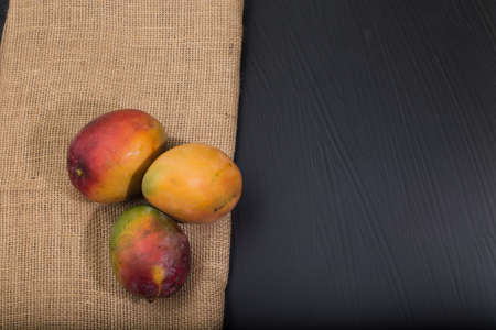 table with mango fruits. dark background with space for text.の写真素材