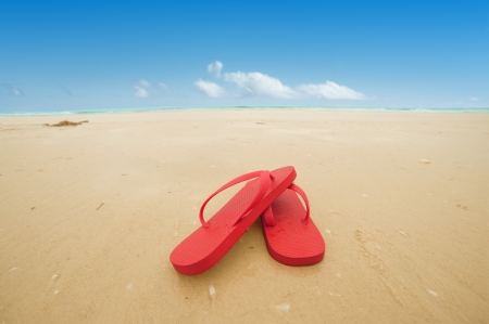 Red flip flops on the beach sand Concept of summer vacationsの写真素材