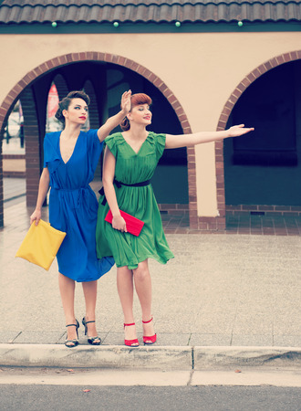 
Two beautiful girls in retro style  hailing  taxi in the streetの写真素材