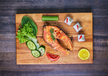 Grilled salmon with vegetables and rice on  wooden plate and on rustic table. Top viewの写真素材