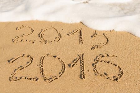 digits  2015 and 2016 on the sand seashore - concept of new year and passing time