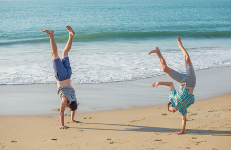 Two young men have fun on the beach  in the evening light.の写真素材