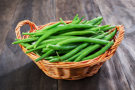Green beans string  in wicker basket on an old wooden black background.Top view.の写真素材
