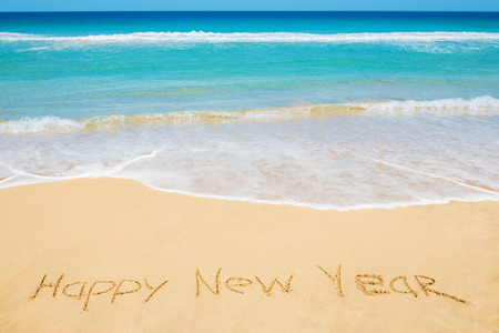Happy New Year message on the beach sand - new year, vacation and travel concept