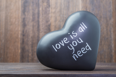 Ceramic black heart on wooden background with message as valentines day symbolの写真素材
