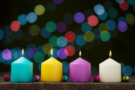 Multicolored burning candles with bokeh on black background.Concept of New Year and Xmasの写真素材